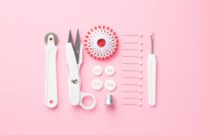 Sewing tools organized over pink background