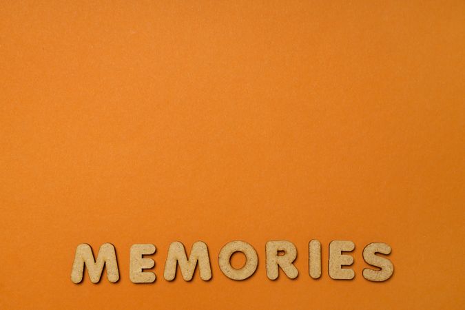 The word “Memories” written in cork on dusty orange background, copy space