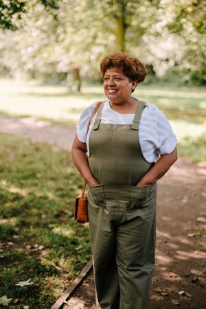 Smiling mature woman with hands in her pocket in park