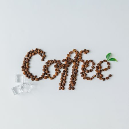 Coffee beans spelling out “Coffee” with ice cubes on bright background