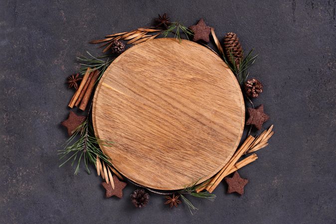 Wooden circle cutting board surrounded with winter spices