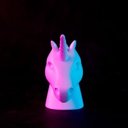 Painted unicorn head in bold pink and blue neon colors on dark background