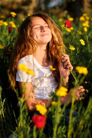 Happy girl with closed eyes in blooming meadow