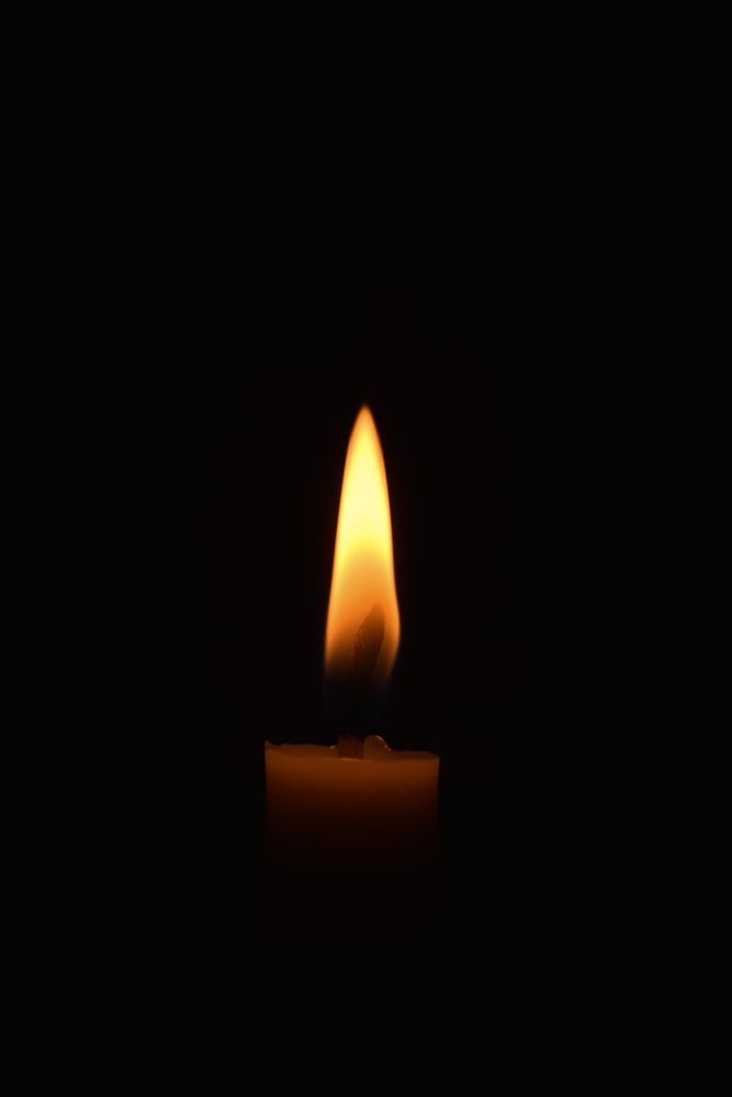Side view of candle lit in the dark with copy space