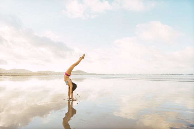 Woman doing handstand near sea