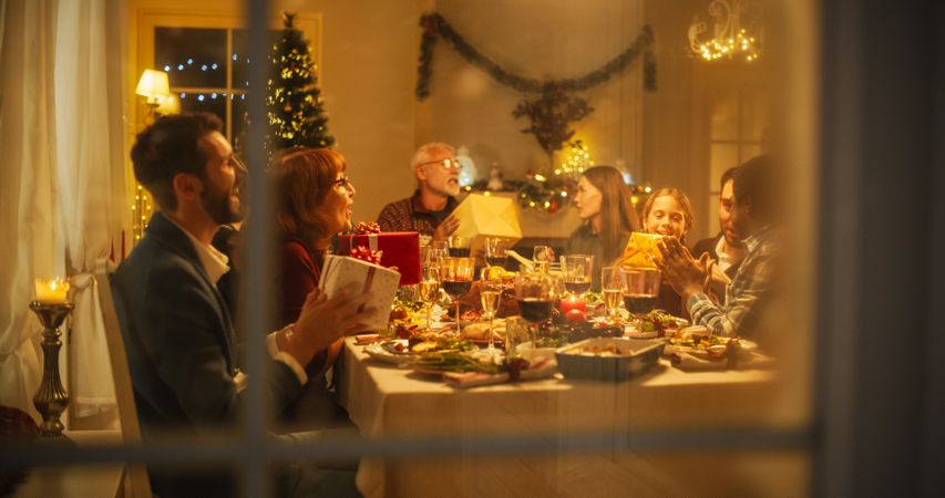 Snowy House Window: Diverse Family Exchanging Christmas Gifts to Celebrate Christmas.