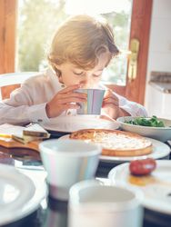 Little boy drinking beverage in morning at home