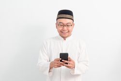 Asian Muslim man smiling holding phone pose, Ramadan