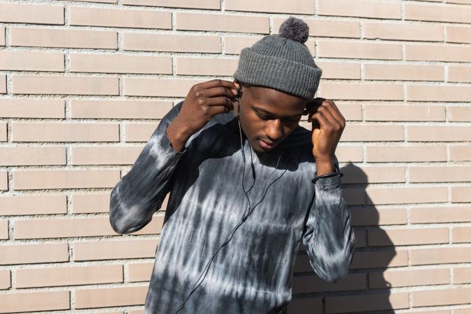 Black man enjoying music from earphones outdoors