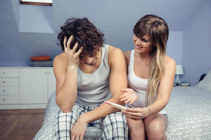 Woman showing pregnancy test to worried man