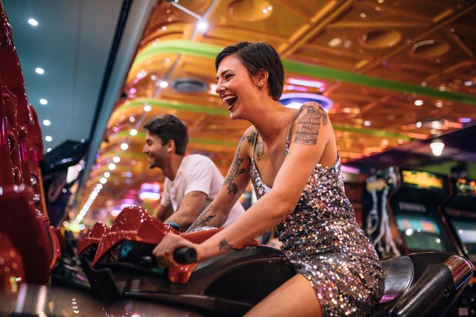 Excited woman playing a racing game sitting on an arcade racing bike