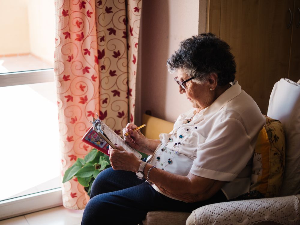 Mature woman solving crosswords in apartment