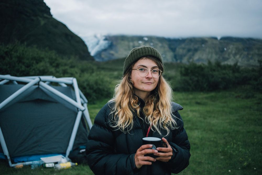 Woman with warm drink in front of tent