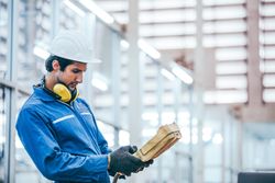 Male mechanic engineer using equipment to control machine in factory