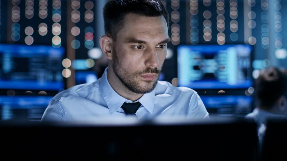 Close-up of a Professional Technical Controller Sitting at His Desk with Multiple Displays Before Him.