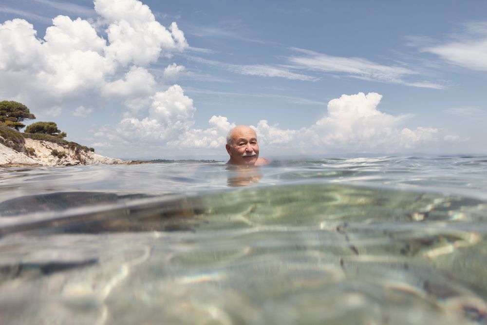 Cheerful older man swimming in sea water