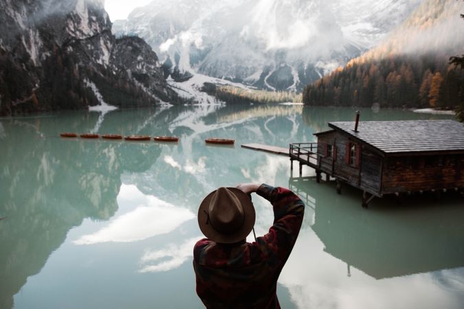 Resting man in casual wear delighting in views near lake and mountains