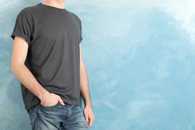 Men in blank grey t-shirt against blue background, space for text