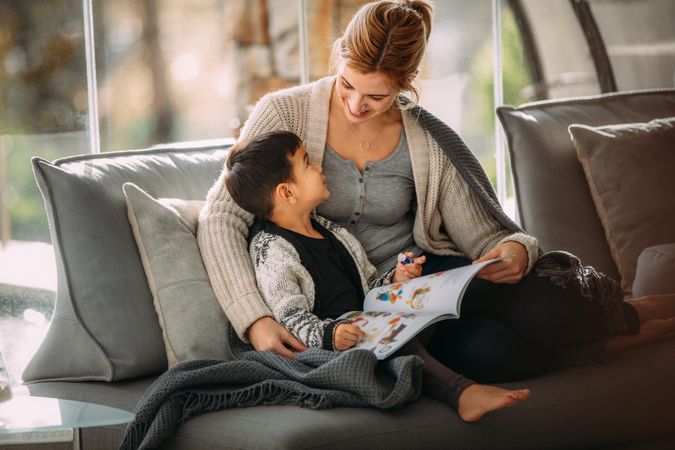 Happy mother and son sitting on couch with a story book living room