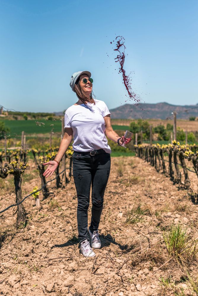 Excited woman spilling red wine from glass in hands