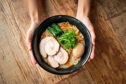 Crop person holding bowl with ramen