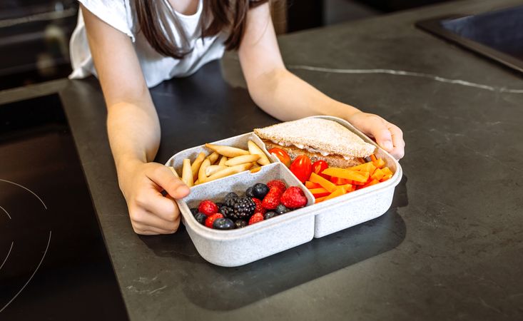 Unrecognizable girl taking lunch box filled with healthy food