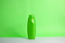 Green body wash bottle with no labels on counter with green background
