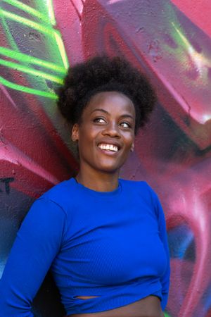Black woman standing near wall with graffiti