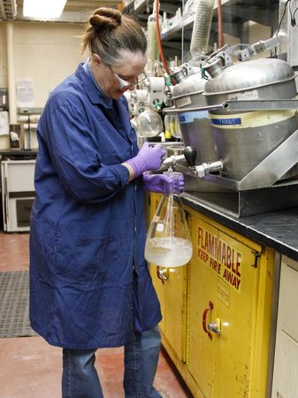 Fort Detrick, MD - USA, Feb 2011: Female scientist preparing solvent mixture from plants