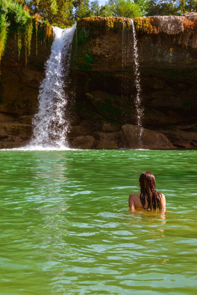 Anonymous female standing near amazing waterfall