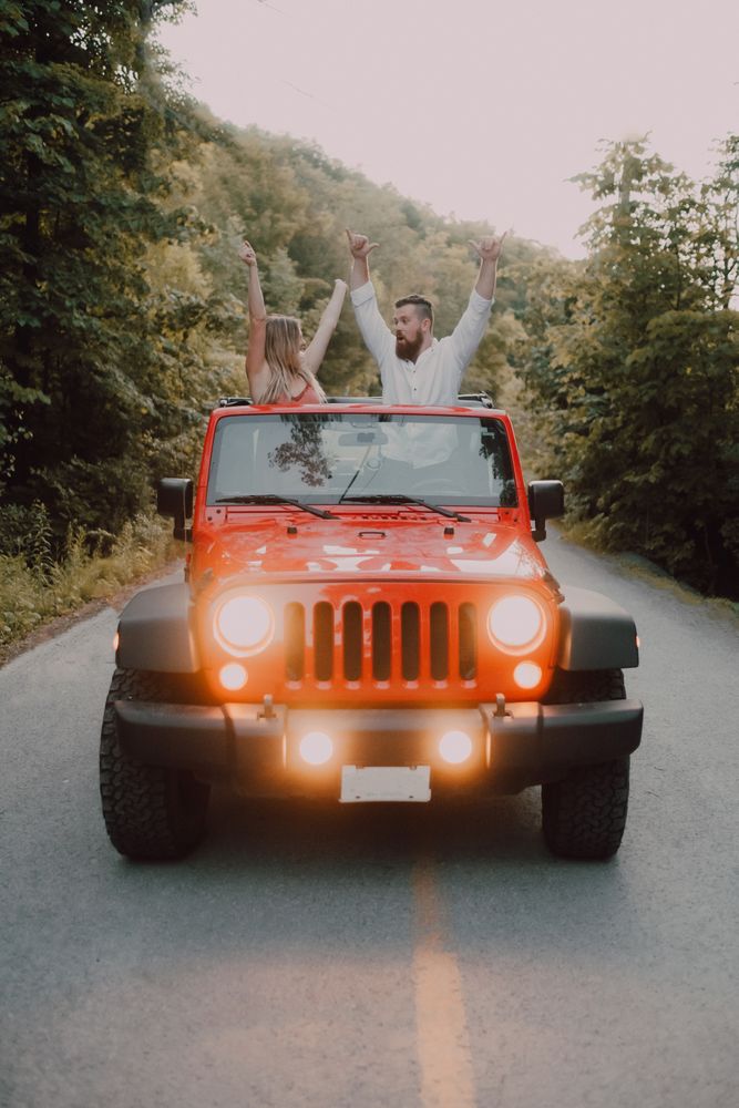 Loving couple sitting on car on road near forest
