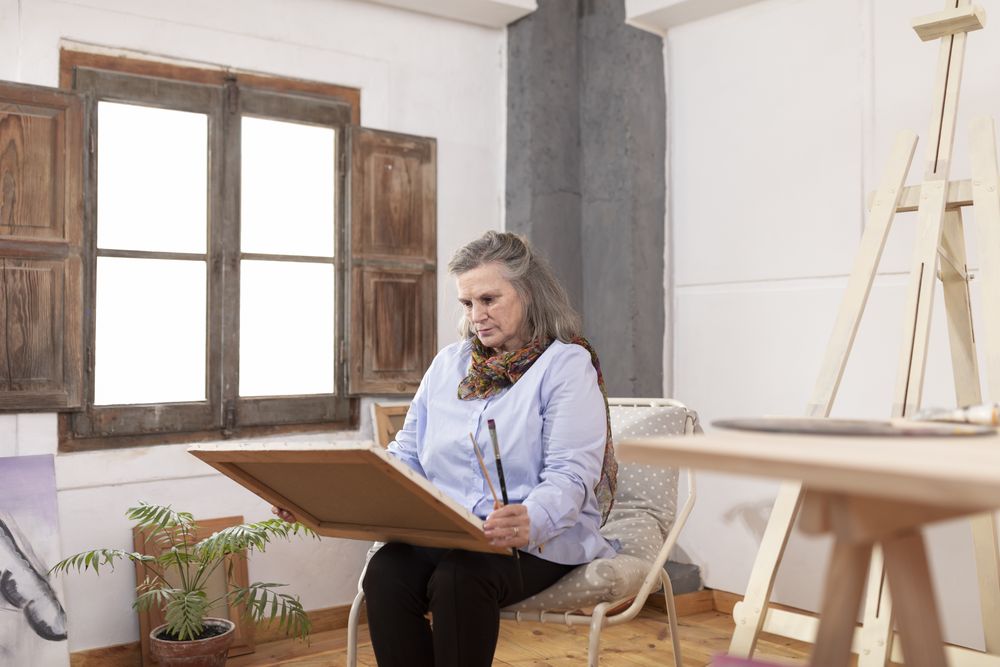 Mature artist woman beholding one of her works
