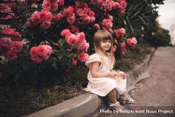 Blonde girl sitting beside pink floral tree 4Aw1R0