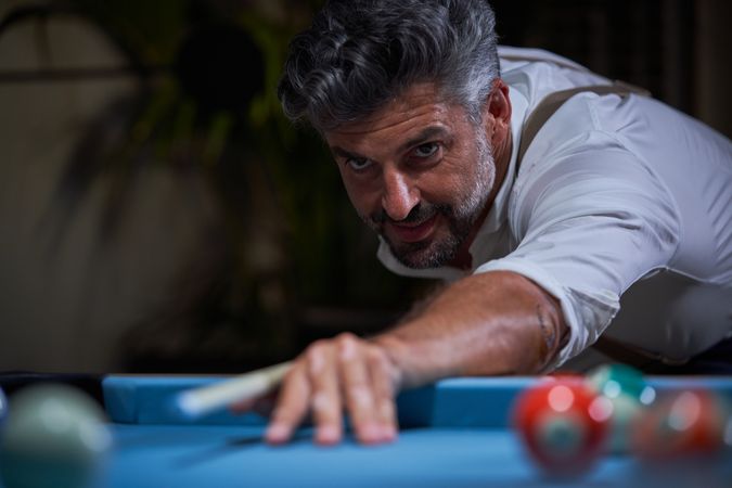 Positive man playing billiards at home
