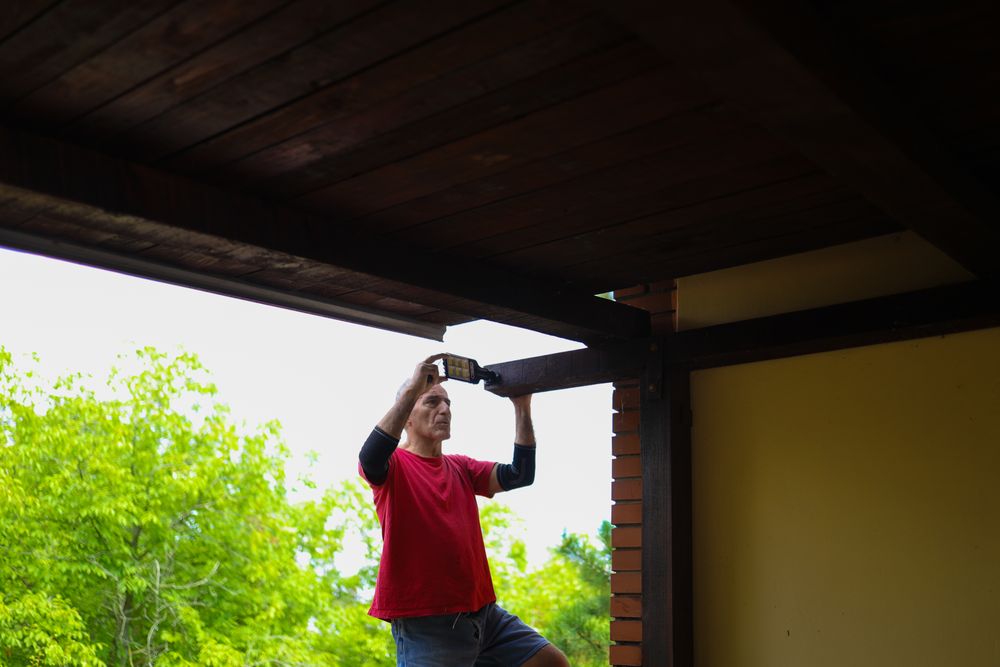 Older man installing a light on his home.