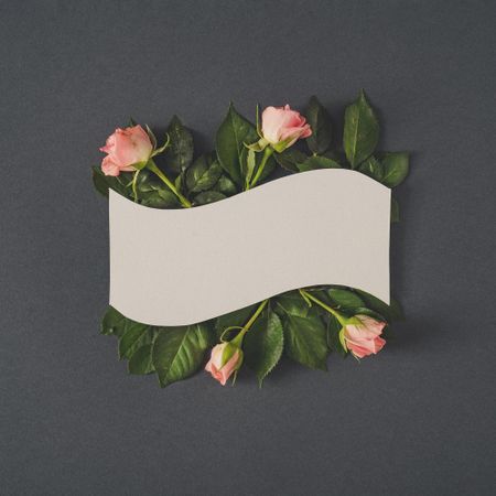 Paper card note with pastel pink rose flowers on dark gray background
