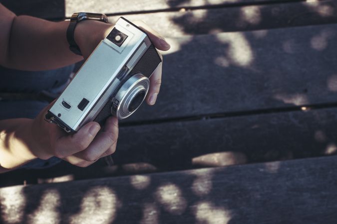 Woman with photo camera sitting and looking along in sunny day
