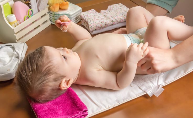 Hands of parent changing diaper of baby