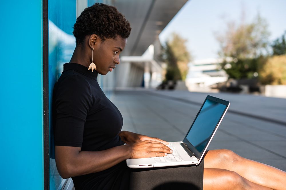 Serious female surfing laptop near modern building