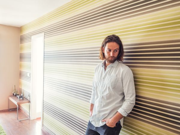 Handsome male standing with hand in pockets in modern room