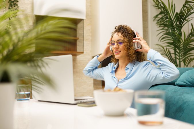 Cheerful woman enjoying music over headphones while working remotely