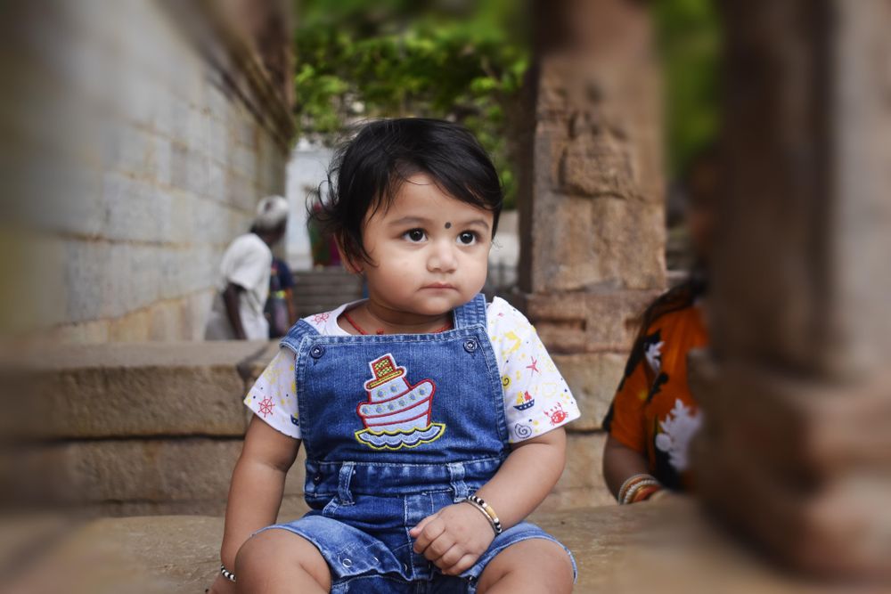Girl in blue denim dungaree sitting on concrete floor outdoor