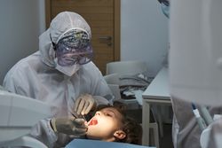 Dentist in medical uniform treating patient in dental office