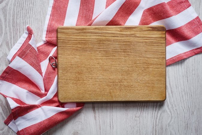 Wooden cutting board on red striped fabric