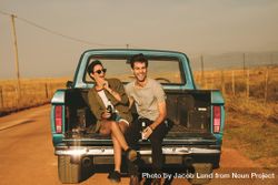 Joyful man and woman holding bottled drinks enjoying country road trip 5RoVD4