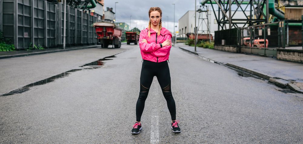 Sporty woman looking camera posing in front of a factory
