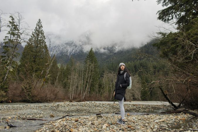 Young woman in the mountains standing near a stream