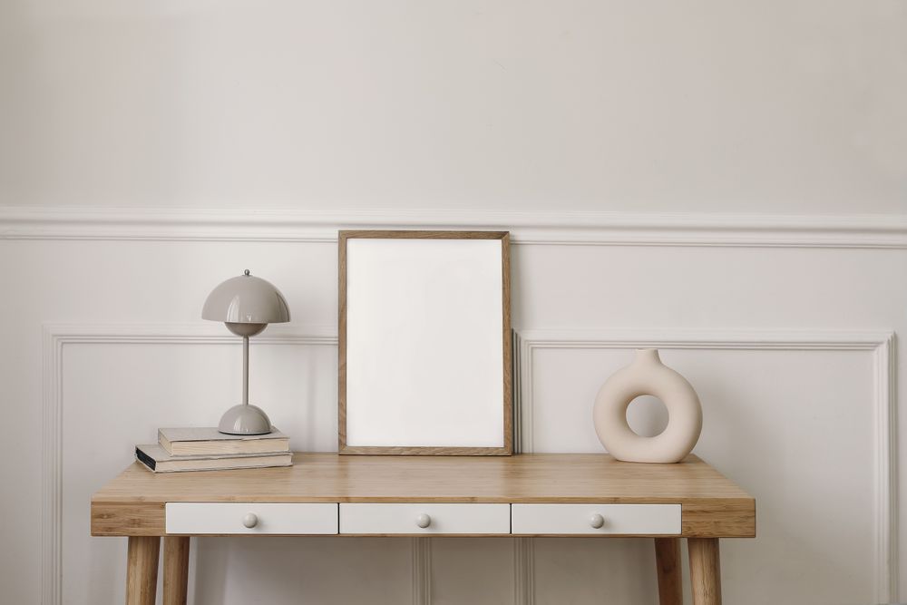 Modern round vase, beige lamp and old books with mock up wooden picture frame