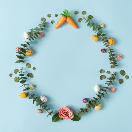 Colorful flowers, carrots, and Easter eggs on blue background