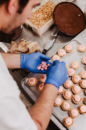 Anonymous baker decorating small cakes